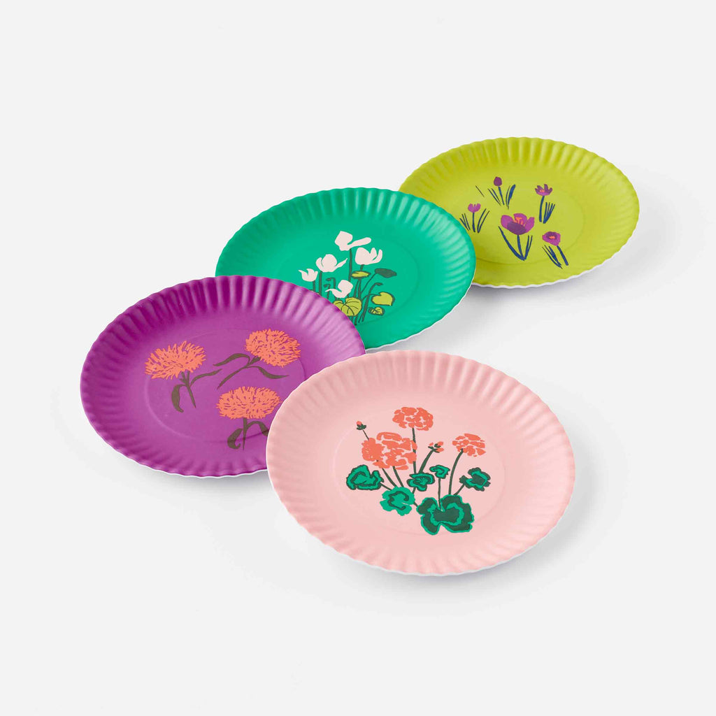 Set of colorful melamine plates on a white background. Coral geraniums on pink, coral mums on purple, pink cyclamen on green, purple crocuses on olive.