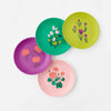Set of colorful melamine plates on a white background. Coral geraniums on pink, coral mums on purple, pink cyclamen on green, purple crocuses on olive.