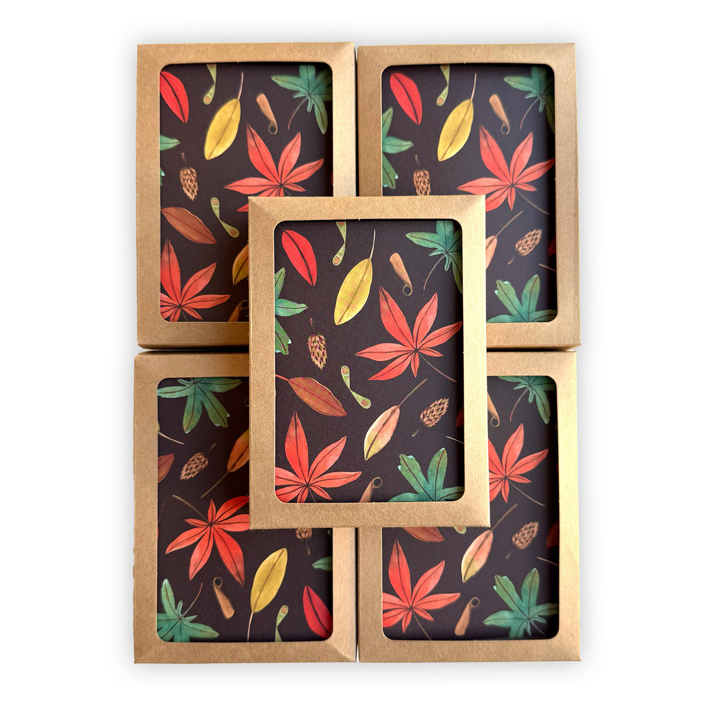 five stacked, boxed notecards featuring a hand painted autumn leaf pattern on a deep chocolate brown background.