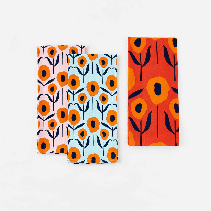 Three Screen Printed Tea Towels: Orange and Navy Poppies on a field of pink, aqua, and red. Misha Zadeh for 180 Degrees