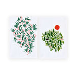Misha Zadeh for 180 Degrees, two vibrant wintery prints screen printed on bright white tea towels. Orange Berries with green leaves and Winter Forest including abstracted evergreen trees, a black bear, an orange fox, and a tawny deer and a large orange sun.