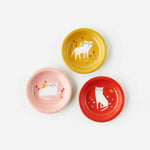 Three small metal trinket dishes with white cat artwork. Pink, Red, and orange background colors.