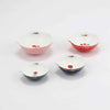 Set of four ceramic measuring ups by Misha Zadeh. Pink, Red, Navy and Teal exteriors with different floral illustrations inside the bowls. Each features a pouring spout and gold detailing throughout.