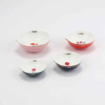 Set of four ceramic measuring ups by Misha Zadeh. Pink, Red, Navy and Teal exteriors with different floral illustrations inside the bowls. Each features a pouring spout and gold detailing throughout.