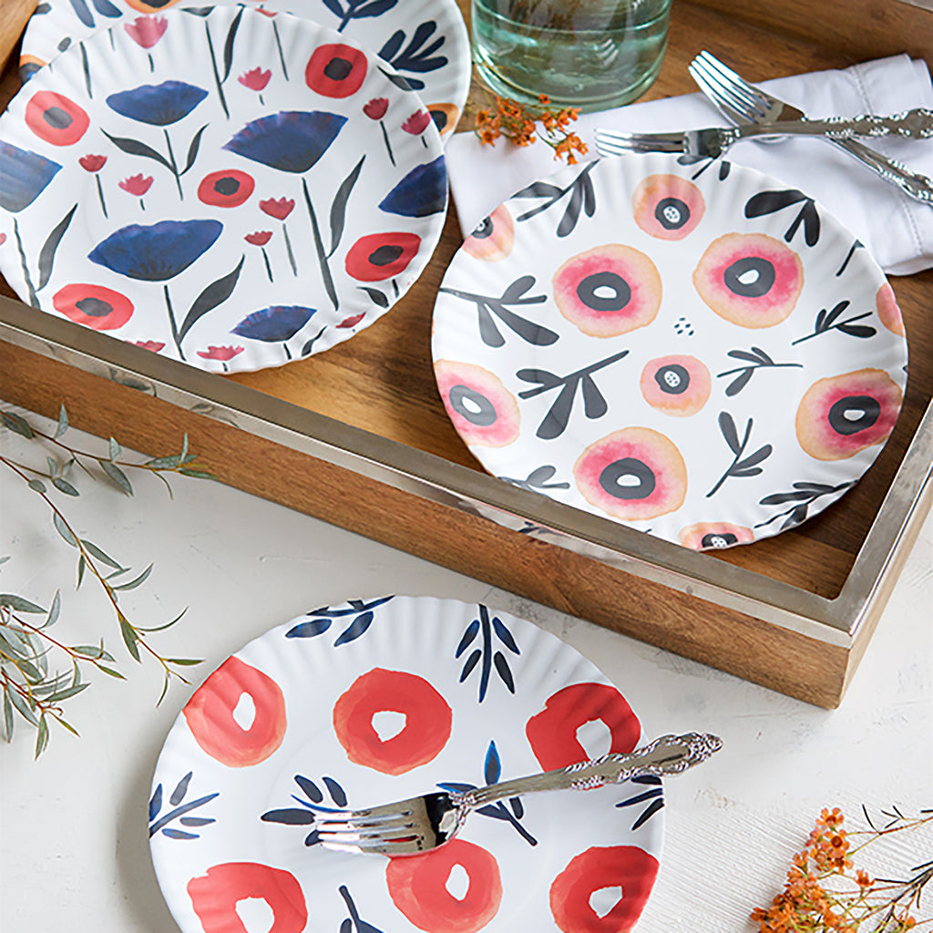 Misha Zadeh 9 inch poppies melamine plates in a styled photo with silverware, glassware, a wood tray, and some flowers