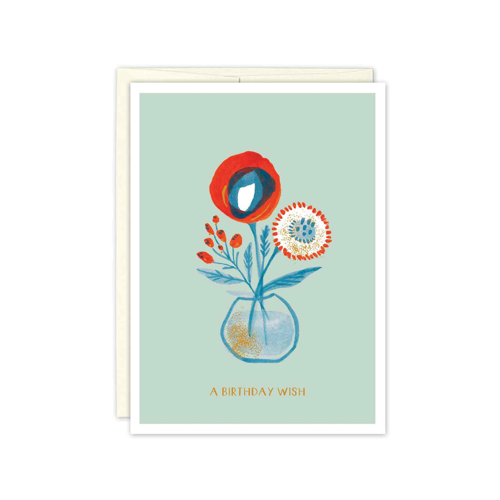 red and blue poppies, mum, and berries in a small round vase with gold detailing. Text reds, "a birthday wish"