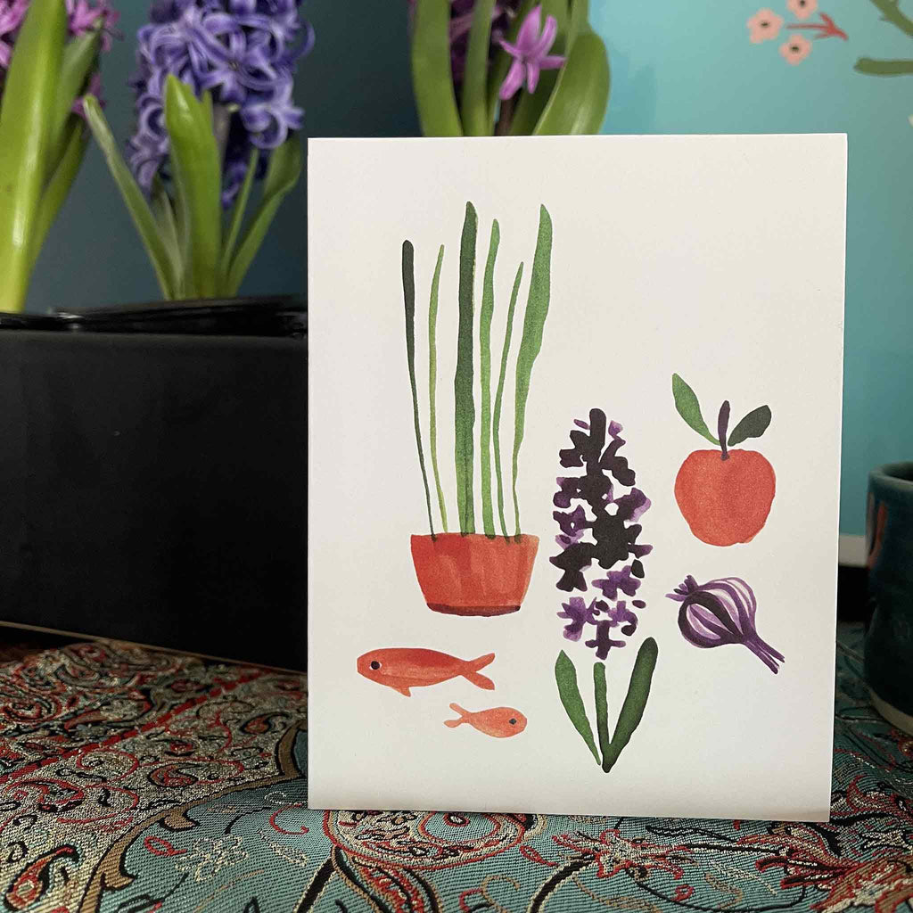 Misha Zadeh Nowruz card on a haft seen table on a termeh textile and purple hyacinths in the background