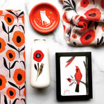 Red themed products by Misha Zadeh including Country Poppies Tea Towel in Pink, Red Poppy Ceramic Bud Vase, Cattitude Small Metal Trinket Dish in Red, Poppy Specimen Modal Scarf in White and a set of Boxed Red Cardinal Joy Holiday Cards
